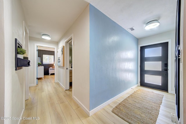 hall with baseboards, light wood-style floors, and visible vents