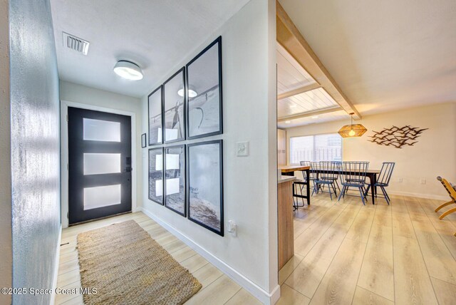 foyer featuring beamed ceiling, baseboards, visible vents, and light wood-style flooring