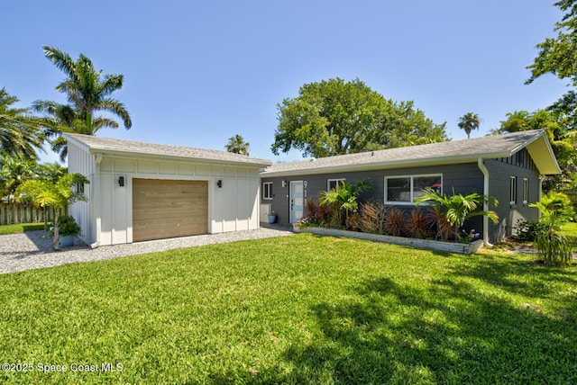 ranch-style home featuring an outdoor structure, board and batten siding, gravel driveway, and a front yard
