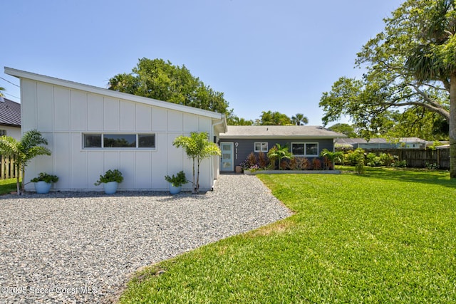 view of front of house featuring fence, board and batten siding, and a front lawn