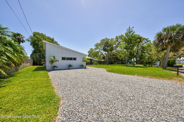 exterior space with board and batten siding, a lawn, and fence