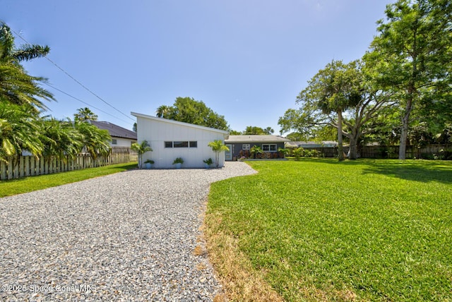 ranch-style home featuring fence, gravel driveway, and a front yard