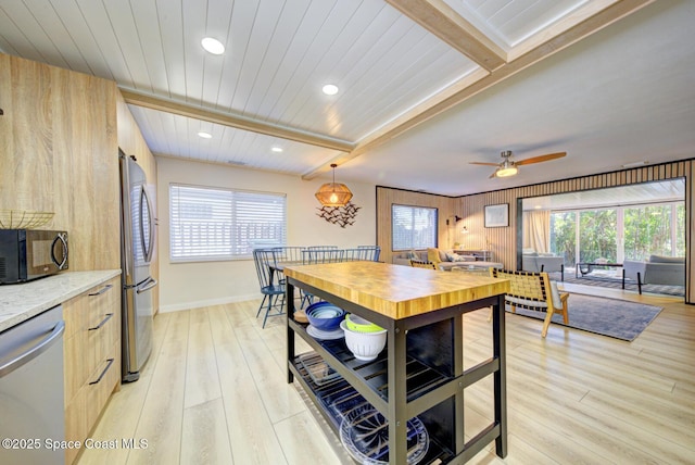 kitchen with ceiling fan, beamed ceiling, appliances with stainless steel finishes, and light wood-style flooring