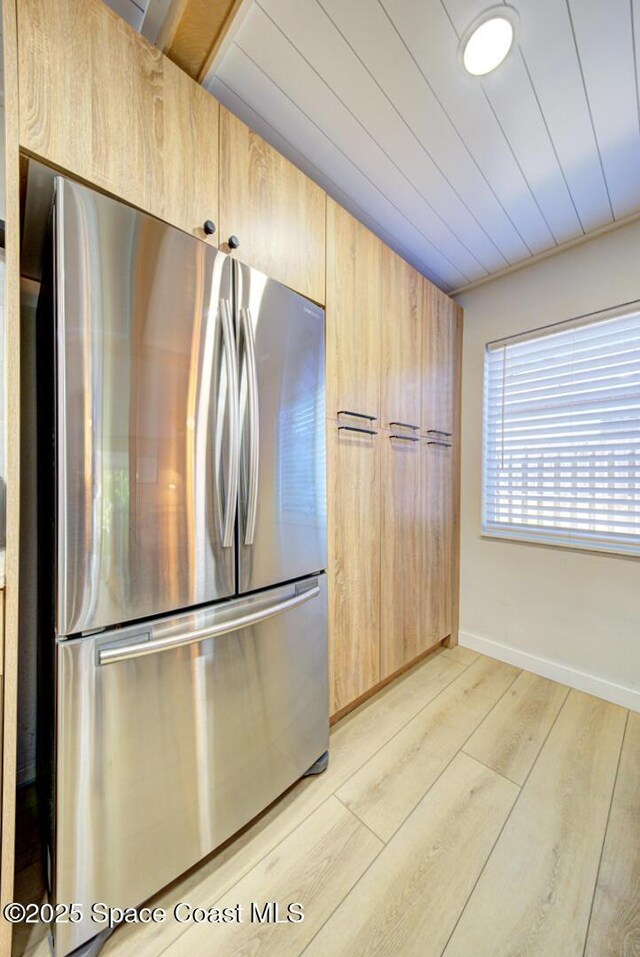 kitchen with baseboards, freestanding refrigerator, light wood finished floors, and light brown cabinets