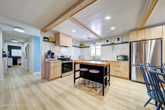 kitchen with appliances with stainless steel finishes, open shelves, light wood-type flooring, a sink, and butcher block countertops