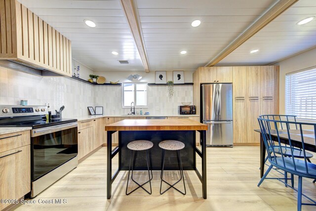 kitchen with decorative backsplash, light brown cabinets, wooden counters, light wood-style flooring, and appliances with stainless steel finishes
