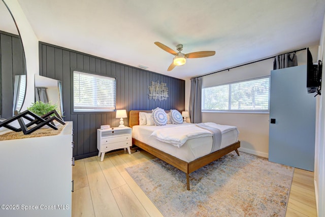 bedroom with light wood-style floors, a ceiling fan, baseboards, and visible vents