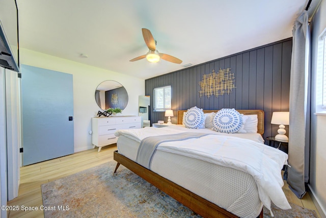 bedroom featuring light wood-style floors, a ceiling fan, and visible vents