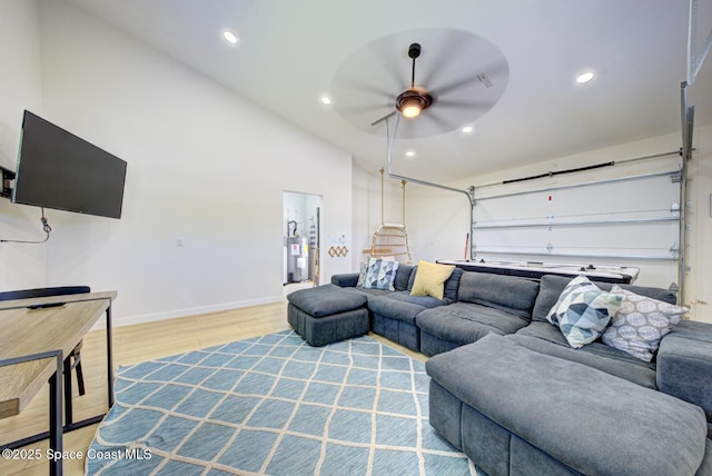 living area with baseboards, ceiling fan, light wood-type flooring, recessed lighting, and water heater