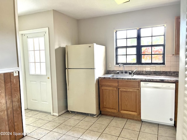 kitchen featuring a sink, plenty of natural light, dark countertops, and white appliances