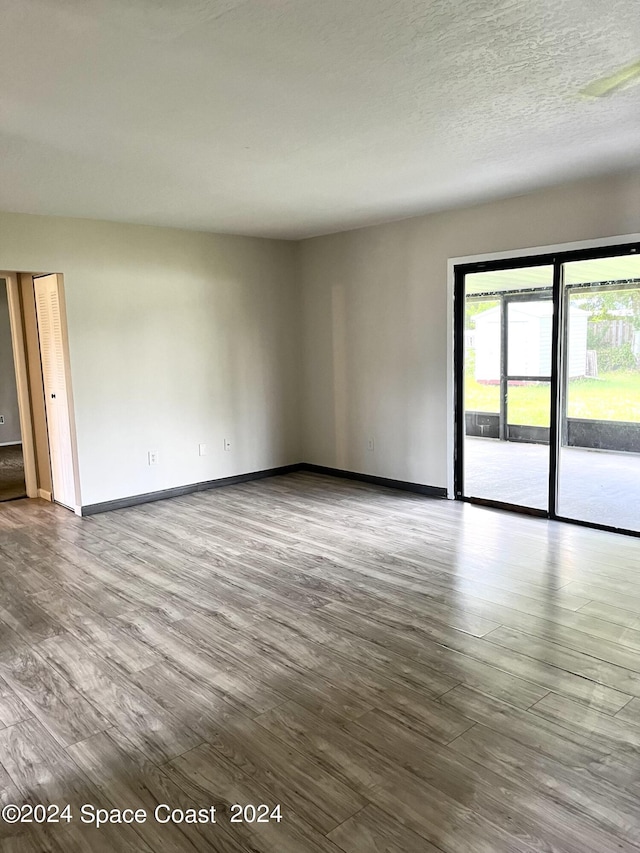 spare room with baseboards, a textured ceiling, and wood finished floors