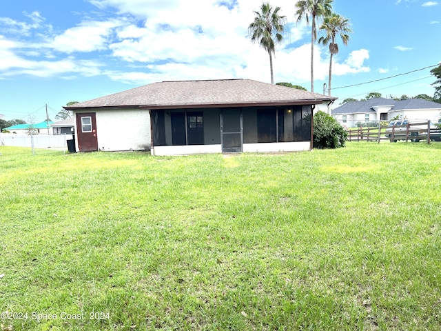 rear view of property featuring a sunroom, fence, a shingled roof, and a yard