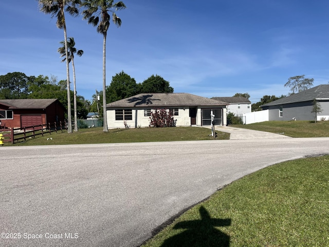 view of front of house featuring a front yard, concrete driveway, and fence
