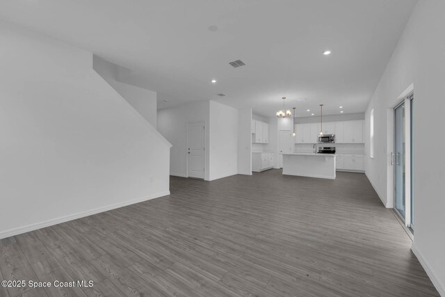 3155 Viridian Cir, Melbourne, FL 32904 - unfurnished living room featuring an inviting chandelier, dark wood-style flooring, recessed lighting, and visible vents
