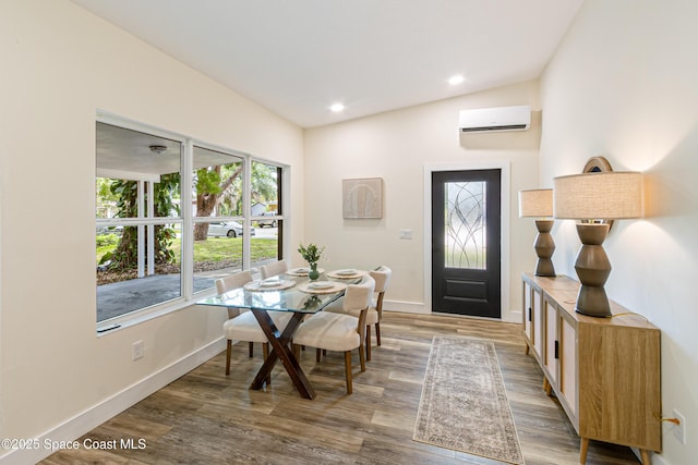 dining area with wood finished floors, a wall unit AC, baseboards, vaulted ceiling, and recessed lighting