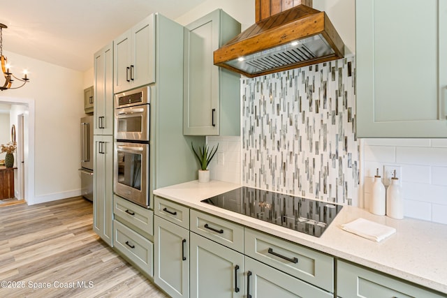 kitchen with custom exhaust hood, an inviting chandelier, green cabinetry, backsplash, and appliances with stainless steel finishes
