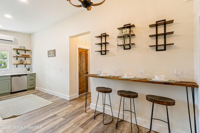 interior space featuring light wood finished floors, a wall unit AC, open shelves, green cabinets, and dishwasher