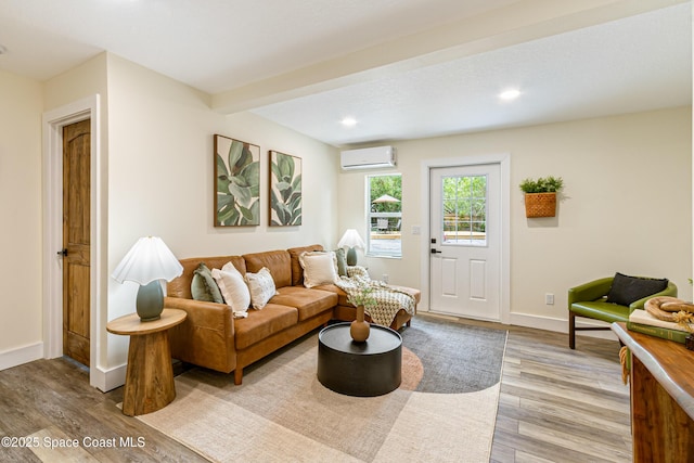 living room featuring recessed lighting, baseboards, a wall unit AC, and light wood-style floors