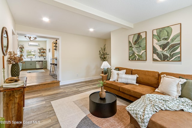living area with a wall mounted air conditioner, beam ceiling, recessed lighting, baseboards, and light wood-style floors