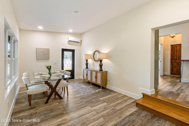 dining room featuring wood finished floors, baseboards, a wall mounted AC, and recessed lighting