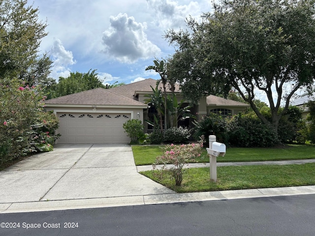 view of front facade featuring a front yard, stucco siding, concrete driveway, and a garage