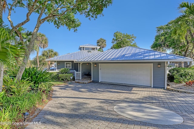 view of front of home featuring an attached garage, metal roof, a standing seam roof, and driveway