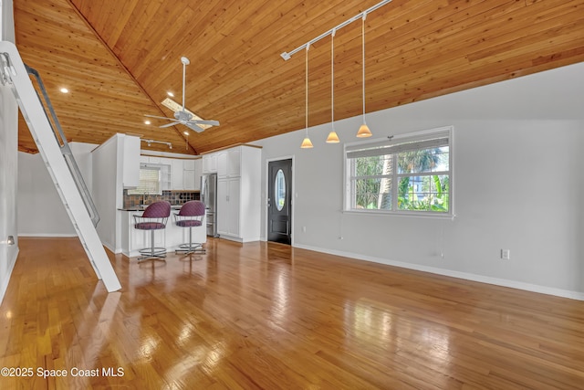 unfurnished living room featuring wood ceiling, baseboards, high vaulted ceiling, light wood-style flooring, and ceiling fan
