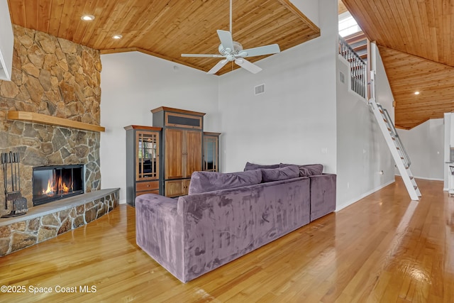 living room featuring wood ceiling, high vaulted ceiling, a ceiling fan, a fireplace, and wood finished floors