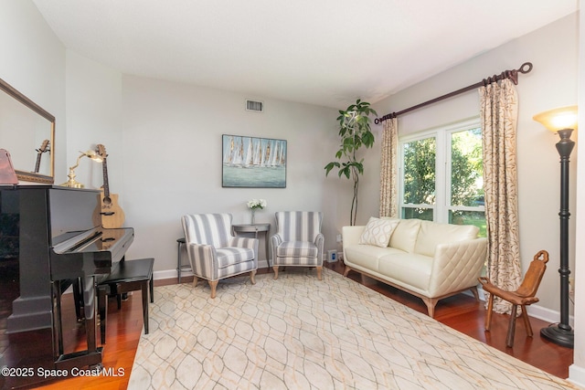living room with baseboards, visible vents, and wood finished floors