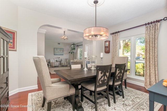 dining room featuring arched walkways, baseboards, an inviting chandelier, and wood finished floors