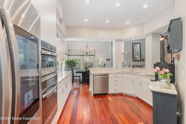 kitchen featuring a sink, light countertops, white cabinets, a notable chandelier, and stainless steel appliances