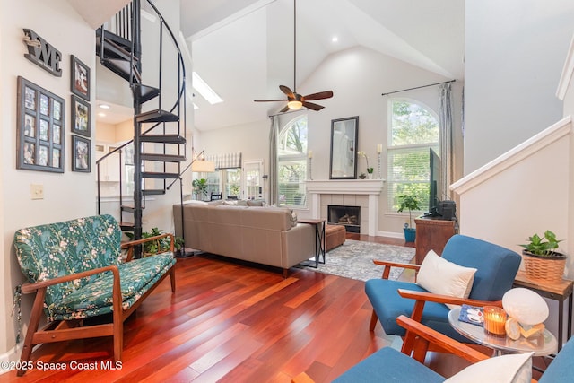 living room featuring a ceiling fan, a fireplace, wood finished floors, high vaulted ceiling, and stairs