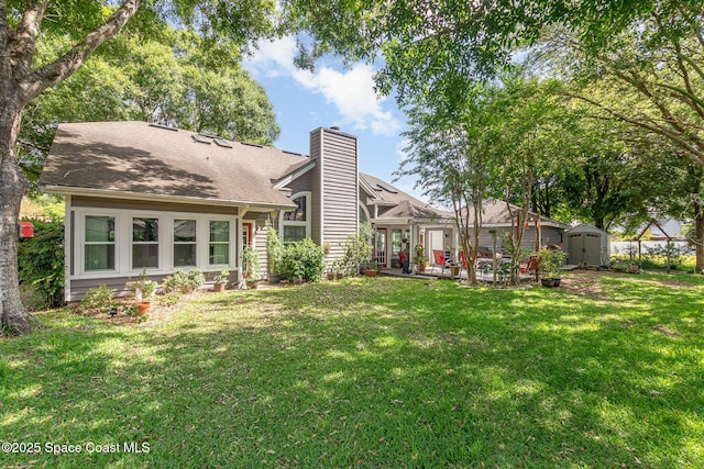 rear view of property featuring a storage unit, an outdoor structure, a lawn, and a chimney