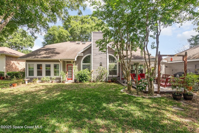 back of house featuring a lawn, roof with shingles, a chimney, and a patio area