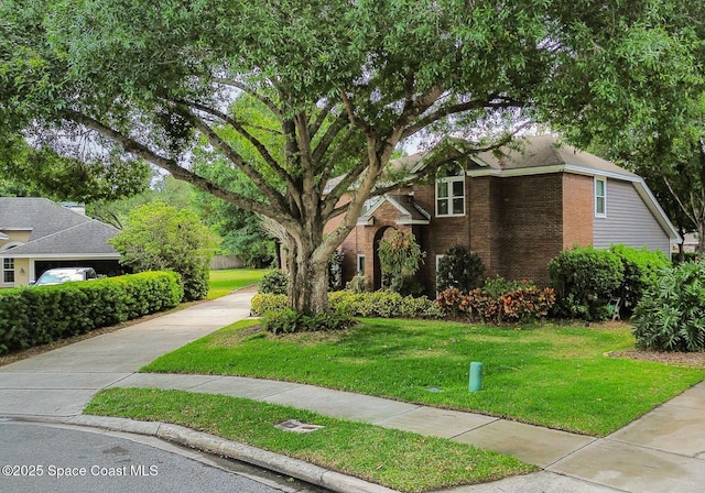 view of front facade with brick siding, a front yard, and concrete driveway