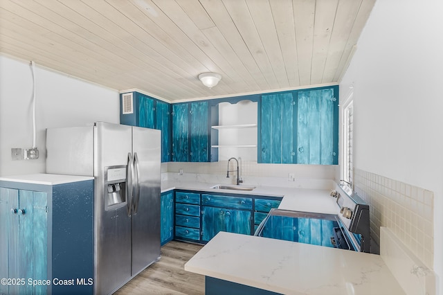kitchen featuring a sink, blue cabinets, open shelves, and stainless steel fridge with ice dispenser