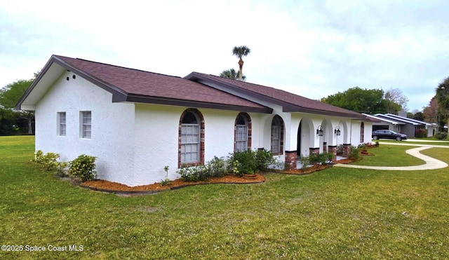 5215 Pina Vista Dr, Melbourne, FL 32934 - view of side of home featuring stucco siding, a yard, and roof with shingles