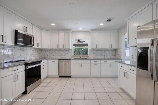 5215 Pina Vista Dr, Melbourne, FL 32934 - kitchen featuring appliances with stainless steel finishes, a sink, decorative backsplash, white cabinetry, and recessed lighting