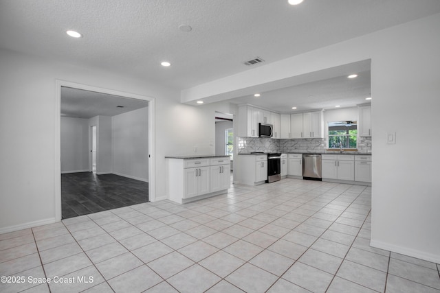 5215 Pina Vista Dr, Melbourne, FL 32934 - kitchen with stainless steel appliances, decorative backsplash, white cabinets, baseboards, and recessed lighting