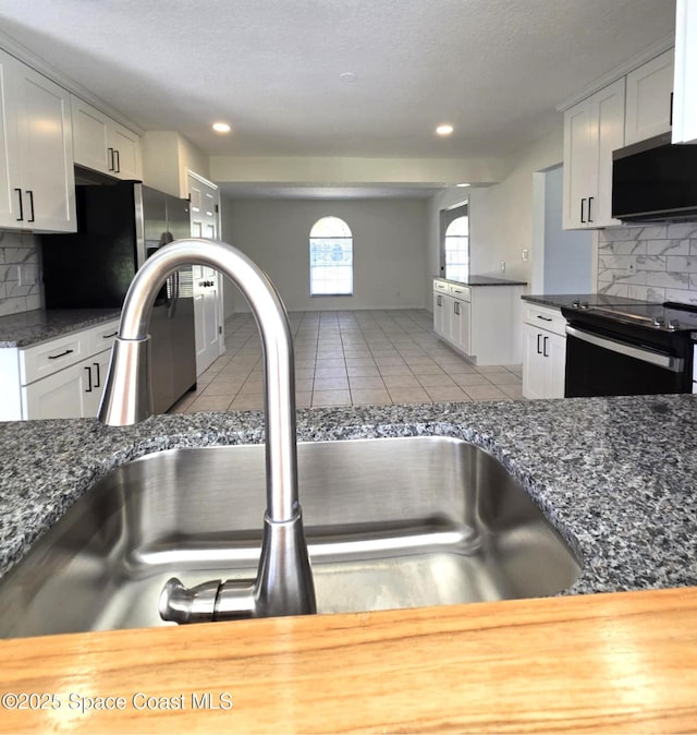 5215 Pina Vista Dr, Melbourne, FL 32934 - kitchen featuring a sink, black range with electric cooktop, stainless steel fridge, backsplash, and light tile patterned flooring