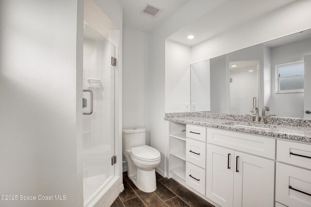 5215 Pina Vista Dr, Melbourne, FL 32934 - bathroom featuring a stall shower, vanity, toilet, wood tiled floors, and recessed lighting