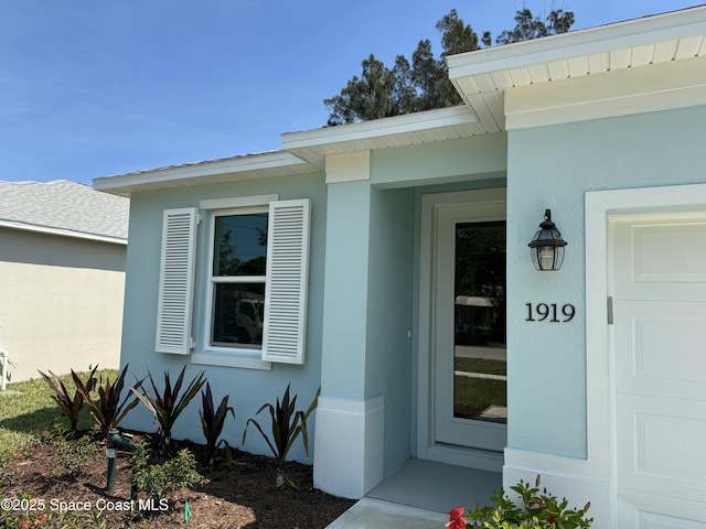 doorway to property featuring stucco siding and an attached garage