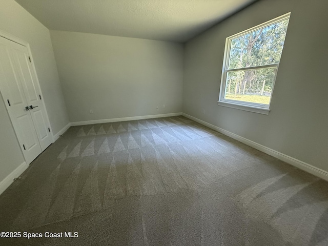 carpeted spare room featuring baseboards and a textured ceiling