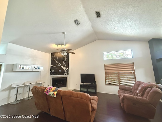 living area featuring visible vents, a textured ceiling, lofted ceiling, and a fireplace