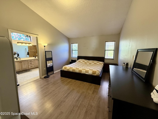 bedroom featuring light wood finished floors, a textured ceiling, multiple windows, and lofted ceiling