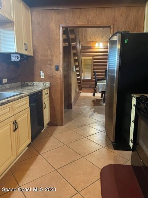 kitchen with dishwasher, light tile patterned floors, a sink, and freestanding refrigerator