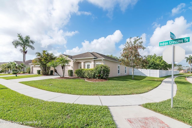 view of front of property featuring stucco siding, fence, a front lawn, an attached garage, and concrete driveway