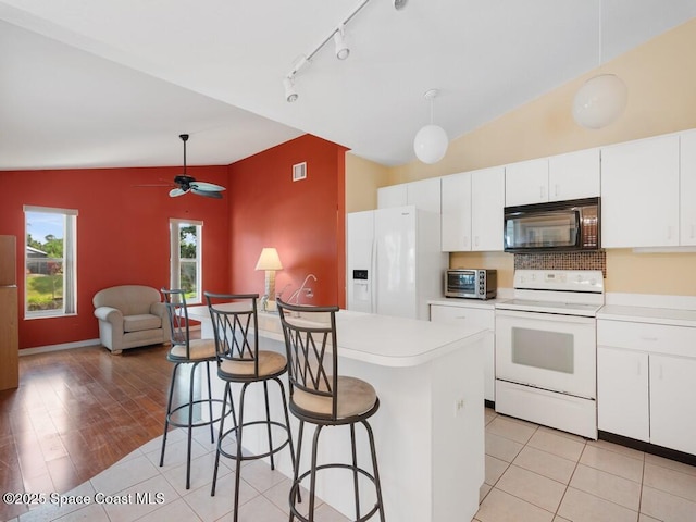 344 Concha Dr, Sebastian, FL 32958 - kitchen with a kitchen breakfast bar, track lighting, a toaster, white appliances, and decorative backsplash