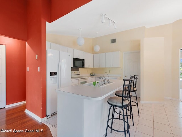 344 Concha Dr, Sebastian, FL 32958 - kitchen with white appliances, a kitchen breakfast bar, white cabinetry, visible vents, and light countertops