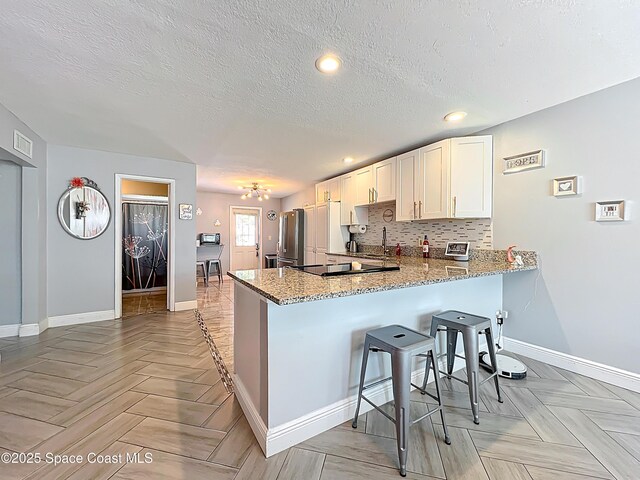 1760 Tee Dee Ln, Titusville, FL 32780 - kitchen with decorative backsplash, light stone countertops, a peninsula, and freestanding refrigerator